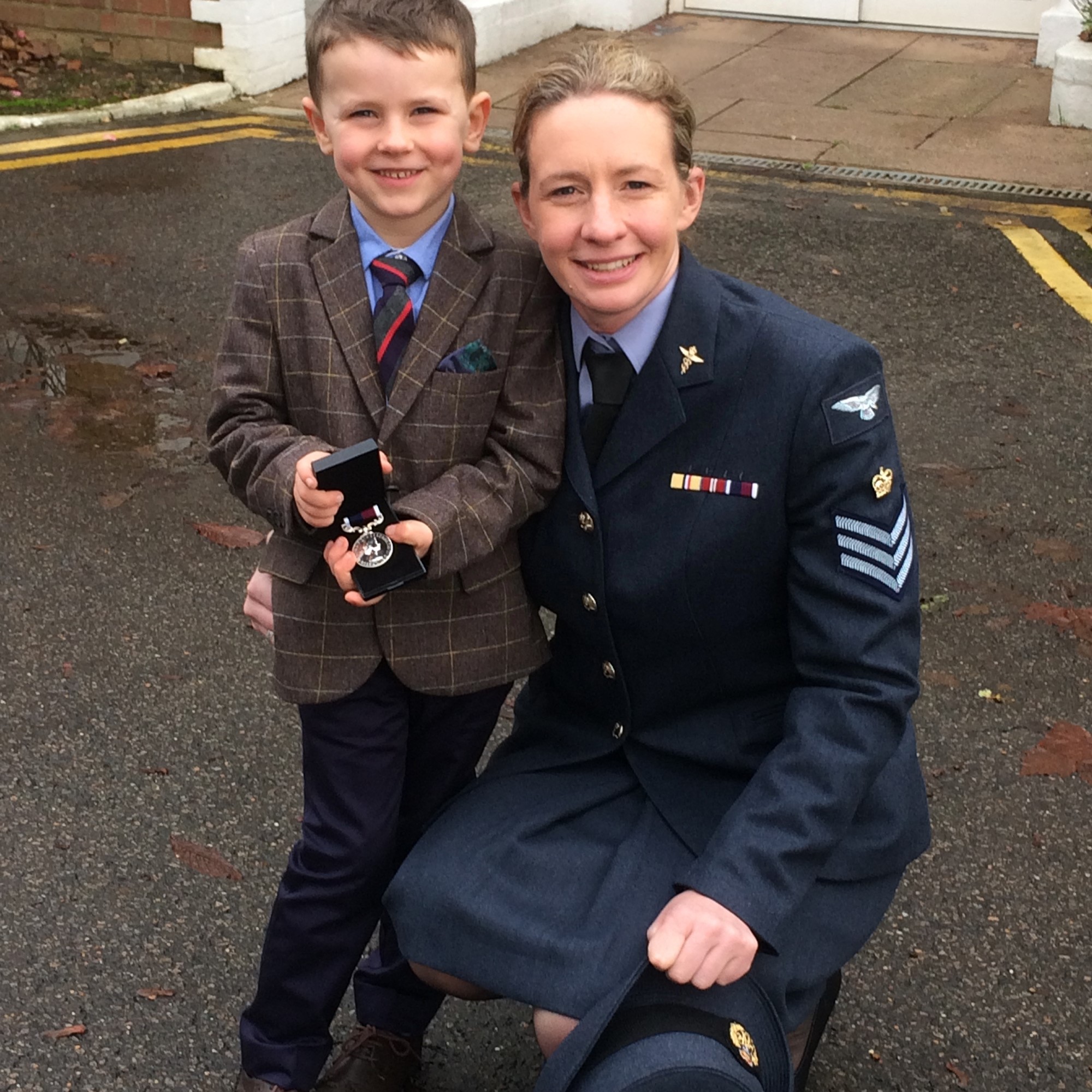 Image shows RAF aviator smiling with her son, who is holding her medal.